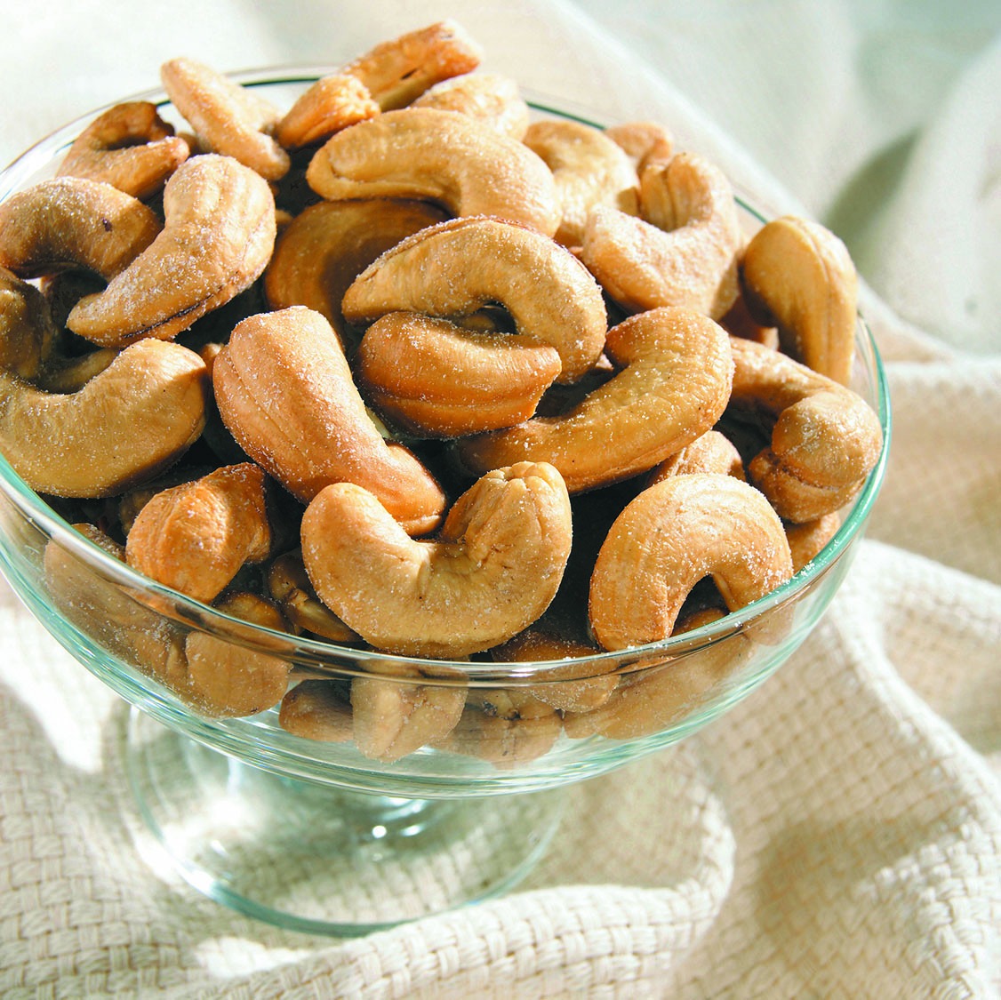 Roasted whole cashews in a glass bowl